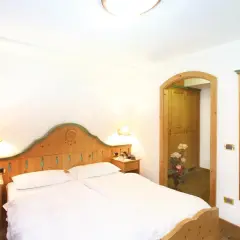 Camera accogliente con letto matrimoniale, arredi in legno e un'apertura verso un armadio. Il tuo soggiorno al hotel Diamant Park sarà rilassante.
