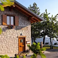 Rifugio Predaia, un'accogliente costruzione in pietra con tetto spiovente, circondato da alberi verdi e un cielo azzurro.