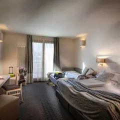 A hotel room with two beds, a desk, and a TV.