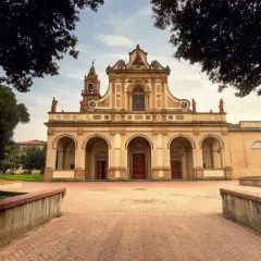 La facciata imponente di una chiesa a Castel Fiorentino, con un portico ad archi e un campanile.