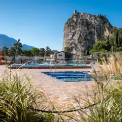 Piscina con scivoli rossi e montagne sullo sfondo, ideale per un soggiorno in campeggio ad Arco.