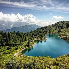 I laghi di San Giuliano, incastonati tra montagne e foreste di conifere, riflettono un cielo azzurro con nuvole bianche.