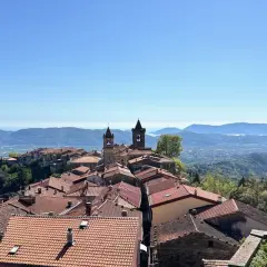 Panoramica di un borgo collinare con tetti rossi e campanili, che rivela dove si trova Fosdinovo, con il mare e le montagne all'orizzonte.