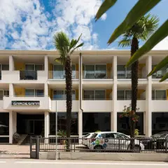 Hotel Gardesana a Riva del Garda, con palme e cielo azzurro. Un'auto bianca parcheggiata davanti.