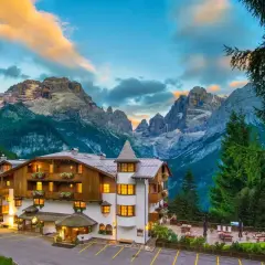 Un incantevole hotel alpino a Madonna di Campiglio, con le maestose Dolomiti sullo sfondo al tramonto.
