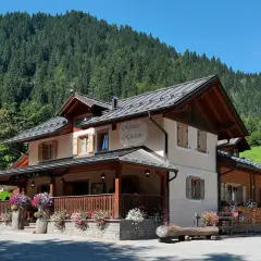 Rifugio Refavaie, un'accogliente struttura alpina con un portico fiorito, immersa nel verde di un bosco di conifere.
