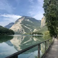 Passeggiata sul lungolago di Toblino, con montagne maestose che si specchiano nelle acque calme.