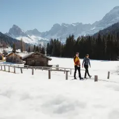 Coppia in escursioni invernali Trentino, tra baite innevate e montagne maestose.