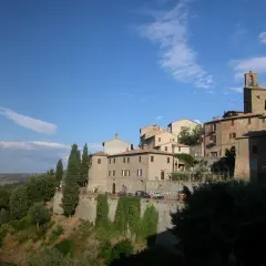 Borgo medievale di Panicale, Perugia, con case in pietra e mattoni, cipressi e vista sulla campagna umbra sotto un cielo azzurro.