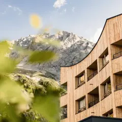 Il Falkensteiner Hotel Antholz si fonde con le maestose montagne. Architettura moderna in legno e natura incontaminata.