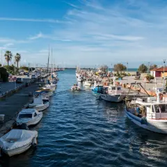 Porto di Viareggio con barche ormeggiate e un faro bianco. Ideale per scoprire cosa fare a Viareggio, tra passeggiate sul molo e gite in barca.