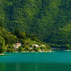 Case aggrappate alla collina verdeggiante che si specchia nel lago di Ledro, un'oasi di pace.