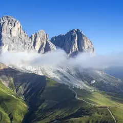 Vette maestose delle Dolomiti avvolte da nuvole, con un sentiero che sale verso il rifugio Col Rodella.