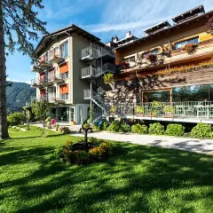 Il la roccia wellness hotel, con la sua facciata in legno e le terrazze fiorite, si affaccia su un prato verde curato, invitando al relax.