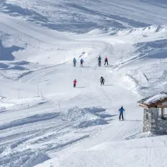 Sciare su piste battute, un piccolo rifugio in pietra e sciatori che godono della loro settimana bianca.