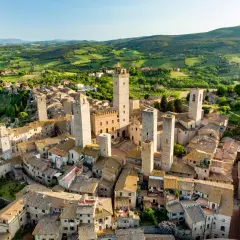 San Gimignano, con le sue torri medievali che svettano tra i tetti di pietra, domina un paesaggio collinare toscano verdeggiante.