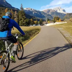 Ciclista su una strada panoramica tra le montagne del Trentino, godendosi le ciclabili.