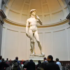 Il David di Michelangelo nella Galleria dell'Accademia di Firenze, ammirato da visitatori.