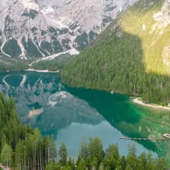 Un lago alpino dalle acque smeraldine, circondato da fitti boschi e montagne imponenti. Un luogo perfetto per le vacanze al lago, con un pontile e un piccolo borgo.