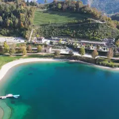 Vista aerea del lago di Ledro con spiaggia e campeggio. Un luogo ideale per il best Ledro camping, con acque cristalline e montagne verdi.