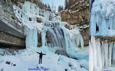 Un uomo in piedi sulla neve ammira le spettacolari cascate vallesinella ghiacciate, con stalattiti di ghiaccio che scendono dalle rocce.