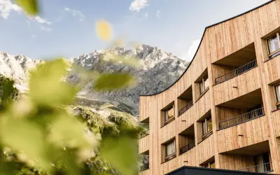 Il Falkensteiner Hotel Antholz si fonde con le maestose montagne. Architettura moderna in legno e natura incontaminata.