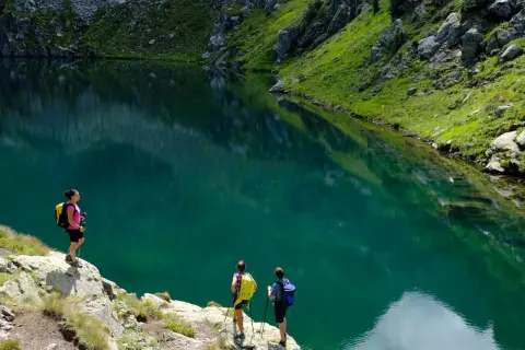 Escursionisti ammirano un lago alpino turchese vicino al bivacco Paolo e Nicola.