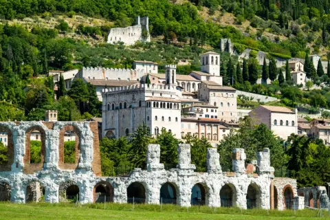 Rovine antiche e borgo medievale a Gubbio, Umbria, con vista sulle colline verdi. Un viaggio da Perugia a Gubbio tra storia e natura.