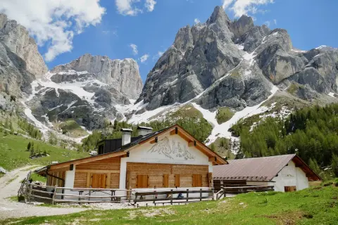 Malga Contrin, un rifugio alpino in legno e pietra, si erge ai piedi di maestose vette dolomitiche innevate.