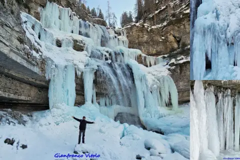 Un uomo in piedi sulla neve ammira le spettacolari cascate vallesinella ghiacciate, con stalattiti di ghiaccio che scendono dalle rocce.