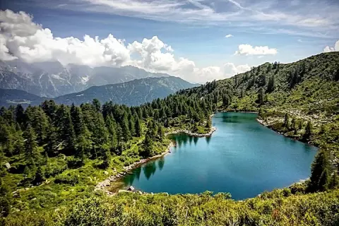 I laghi di San Giuliano, incastonati tra montagne e foreste di conifere, riflettono un cielo azzurro con nuvole bianche.