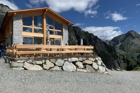 Il rifugio Cornisello, con la sua architettura in legno e pietra, si staglia maestoso tra le vette. Un luogo ideale per una pausa panoramica.