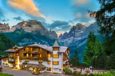 Un incantevole hotel alpino a Madonna di Campiglio, con le maestose Dolomiti sullo sfondo al tramonto.