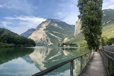 Passeggiata sul lungolago di Toblino, con montagne maestose che si specchiano nelle acque calme.