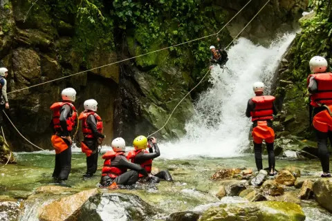 Avventura di canyoning in Trentino: un gruppo si prepara a scendere una cascata, immersi nella natura selvaggia.