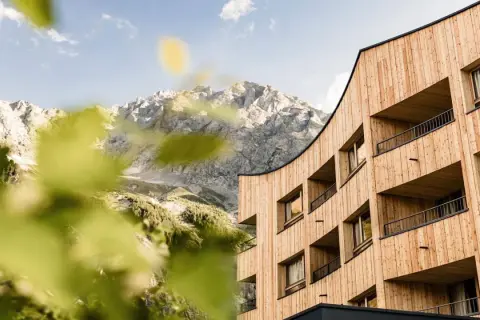Il Falkensteiner Hotel Antholz si fonde con le maestose montagne. Architettura moderna in legno e natura incontaminata.