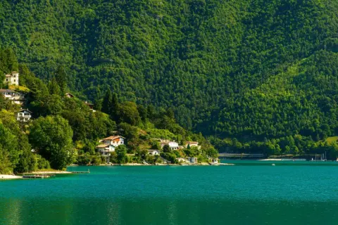 Case aggrappate alla collina verdeggiante che si specchia nel lago di Ledro, un'oasi di pace.