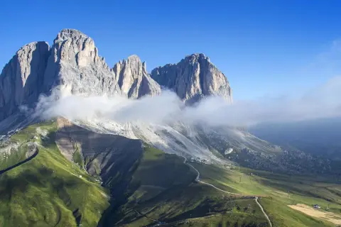 Vette maestose delle Dolomiti avvolte da nuvole, con un sentiero che sale verso il rifugio Col Rodella.