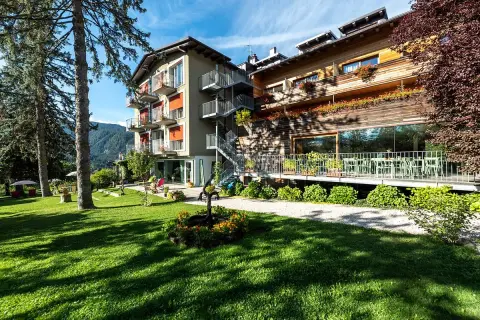 Il la roccia wellness hotel, con la sua facciata in legno e le terrazze fiorite, si affaccia su un prato verde curato, invitando al relax.