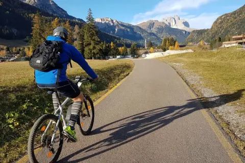 Ciclista su una strada panoramica tra le montagne del Trentino, godendosi le ciclabili.