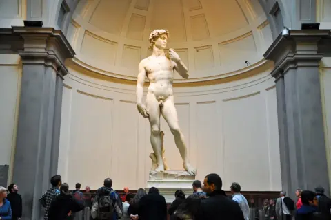 Il David di Michelangelo nella Galleria dell'Accademia di Firenze, ammirato da visitatori.