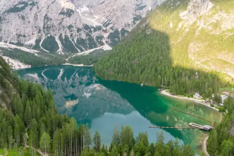 Un lago alpino dalle acque smeraldine, circondato da fitti boschi e montagne imponenti. Un luogo perfetto per le vacanze al lago, con un pontile e un piccolo borgo.
