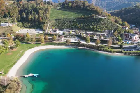 Vista aerea del lago di Ledro con spiaggia e campeggio. Un luogo ideale per il best Ledro camping, con acque cristalline e montagne verdi.