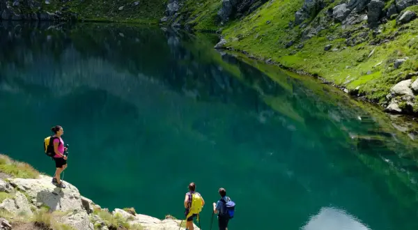Escursionisti ammirano un lago alpino turchese vicino al bivacco Paolo e Nicola.