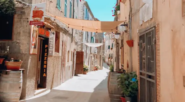 Un vicolo pittoresco con panni stesi, vasi di fiori e una pizzeria. Un luogo incantevole dove passeggiare e scoprire cosa vedere.