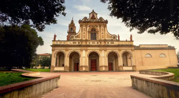 La facciata imponente di una chiesa a Castel Fiorentino, con un portico ad archi e un campanile.