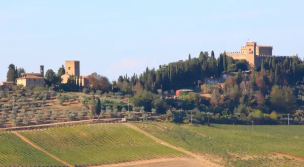 Colline toscane con vigneti e uliveti, e in lontananza castelli e torri, un'idea di cosa vedere a Poggibonsi.