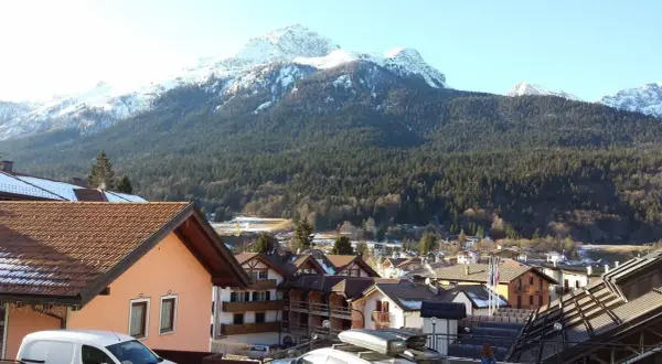 Paesaggio invernale con montagne innevate e un villaggio alpino. Si intravede un hotel ad Andalo.