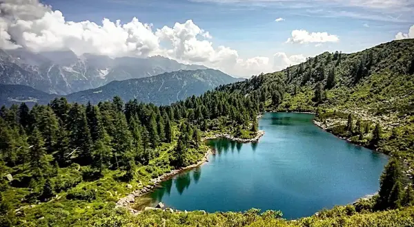 I laghi di San Giuliano, incastonati tra montagne e foreste di conifere, riflettono un cielo azzurro con nuvole bianche.
