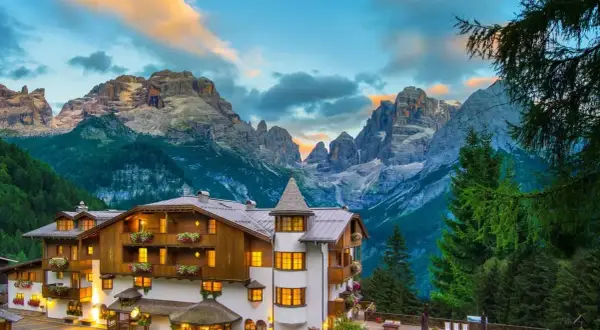 Un incantevole hotel alpino a Madonna di Campiglio, con le maestose Dolomiti sullo sfondo al tramonto.
